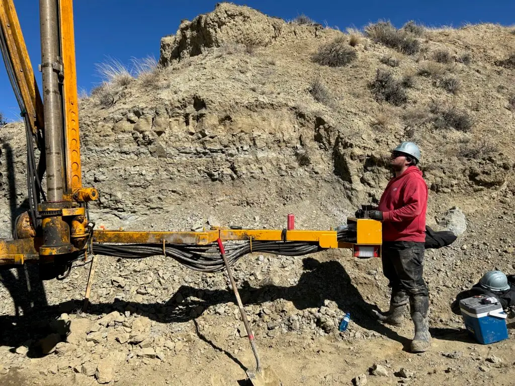 SCION crew member operating a hydraulic rod handler to reduce manual lifting risks on rocky slope.