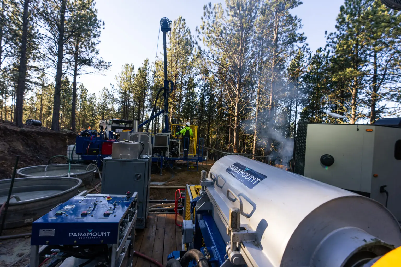 Paramount centrifuge and fluid control system in operation on forested drill pad.